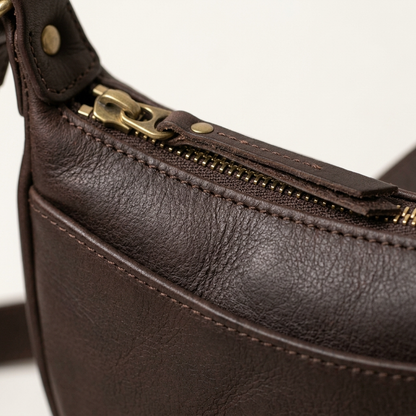 Close-up of brass zip track and leather pull tab on the Aldon crossbody sling